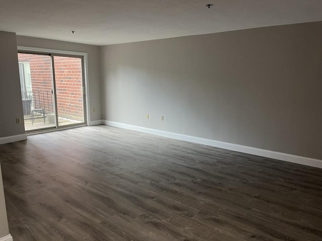 spare room with baseboards and dark wood-style floors