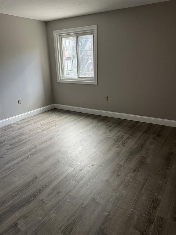 unfurnished room with dark wood-style flooring and baseboards