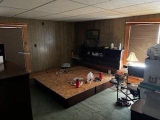 living room with a paneled ceiling and wooden walls