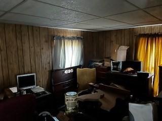 miscellaneous room with a paneled ceiling and wooden walls