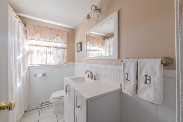 bathroom featuring tile patterned floors, a wainscoted wall, visible vents, toilet, and vanity