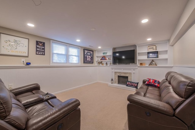 carpeted living area with recessed lighting, a fireplace with raised hearth, built in shelves, and baseboards