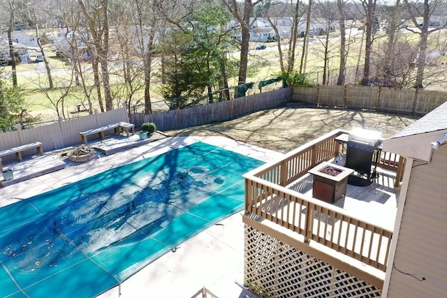 view of pool with a wooden deck, a fire pit, a fenced backyard, and a patio area