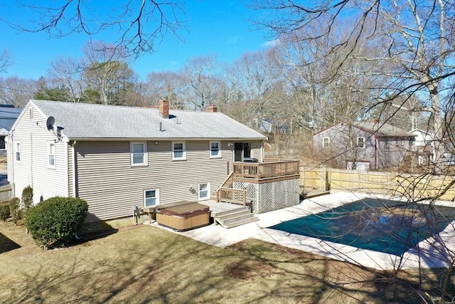 back of house featuring a hot tub, fence, a lawn, a chimney, and a deck