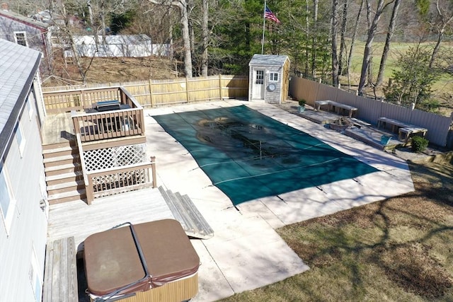 view of swimming pool featuring a storage unit, an outbuilding, a fenced backyard, a wooden deck, and a fenced in pool