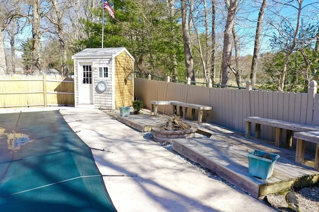 view of patio / terrace featuring a wooden deck, a storage shed, an outdoor structure, and fence