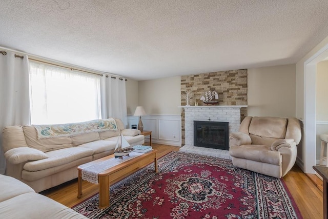 living room with a wainscoted wall, a brick fireplace, and wood finished floors