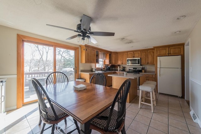 dining room featuring ceiling fan, light tile patterned flooring, baseboards, and a textured ceiling