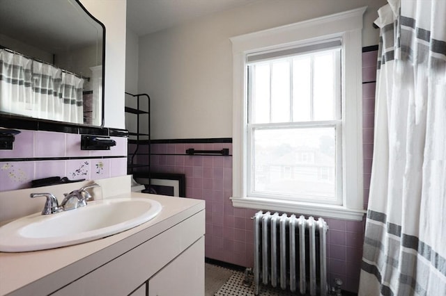 full bathroom featuring radiator, wainscoting, tile walls, and vanity