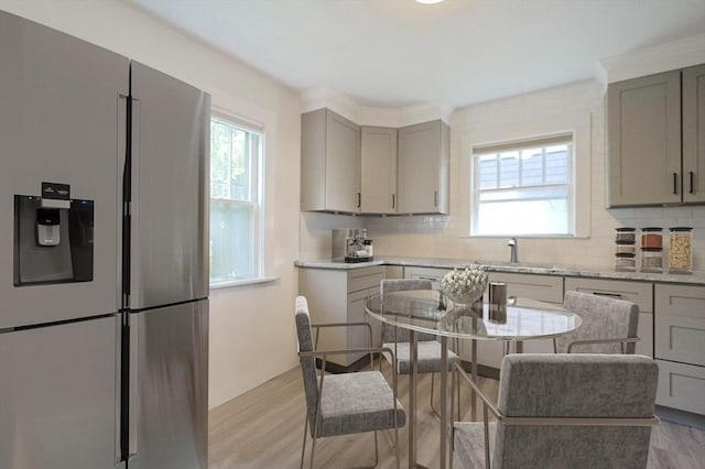 kitchen with backsplash, plenty of natural light, and stainless steel refrigerator with ice dispenser