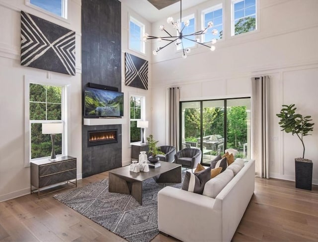 living room with a chandelier, wood-type flooring, and a towering ceiling