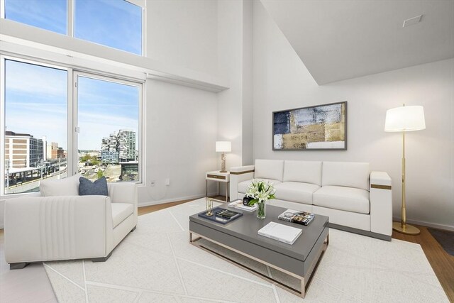 living area with a high ceiling, wood finished floors, baseboards, and a city view