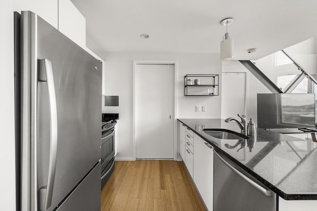 kitchen with appliances with stainless steel finishes, a sink, white cabinetry, light wood-style flooring, and recessed lighting