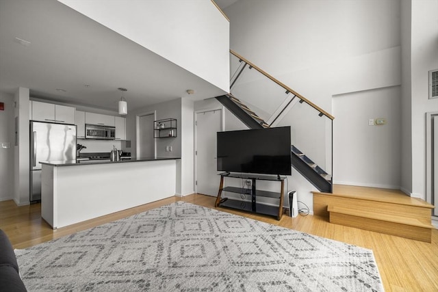 living room featuring stairs, light wood finished floors, and baseboards