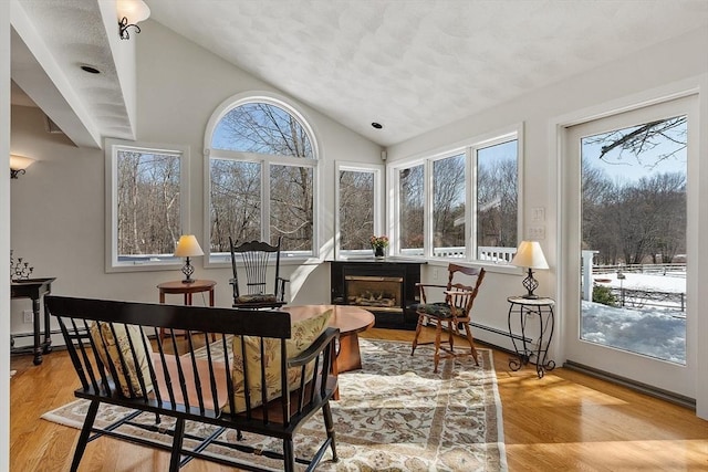 sunroom / solarium with lofted ceiling, a baseboard radiator, and a fireplace