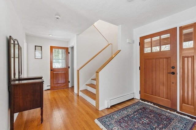 foyer entrance featuring light wood-type flooring, baseboard heating, and stairs