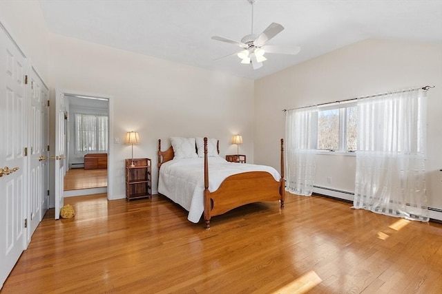 bedroom with light wood-style flooring, a baseboard heating unit, vaulted ceiling, and a ceiling fan