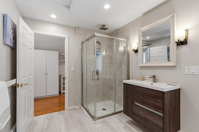 bathroom with a stall shower, wood finished floors, vanity, and recessed lighting