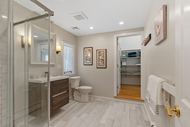 full bathroom with a stall shower, visible vents, toilet, wood finished floors, and vanity