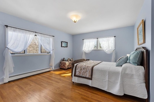 bedroom featuring a baseboard heating unit and wood finished floors