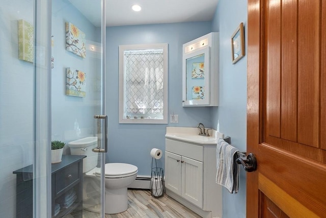 full bathroom featuring toilet, a baseboard heating unit, a stall shower, vanity, and wood finished floors