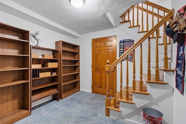 interior space with a textured ceiling, stairway, and dark tile patterned floors