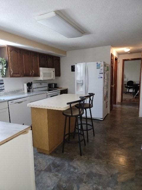 82 Prince Rd, Southbridge, MA 01550 - kitchen with white appliances, light countertops, a breakfast bar, and a textured ceiling