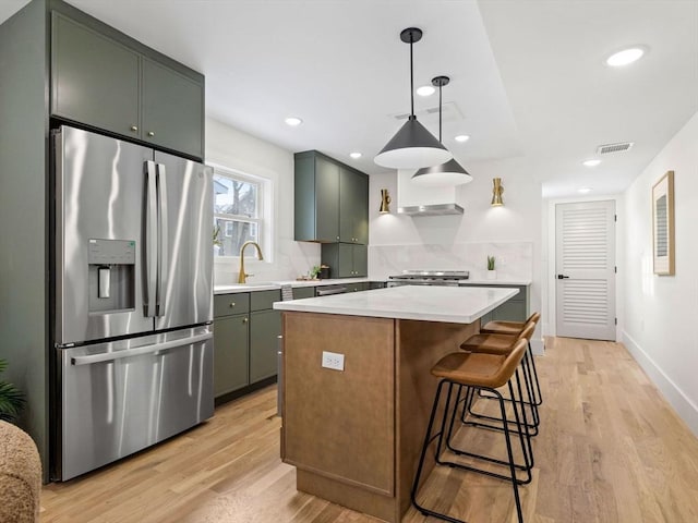 kitchen featuring visible vents, decorative light fixtures, a center island, light countertops, and stainless steel refrigerator with ice dispenser