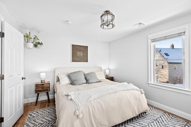 bedroom with hardwood / wood-style flooring and multiple windows