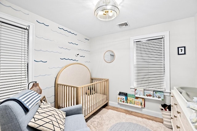 bedroom with light hardwood / wood-style floors and a nursery area