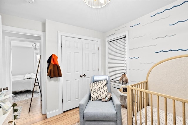 bedroom featuring a crib, light wood-type flooring, and a closet