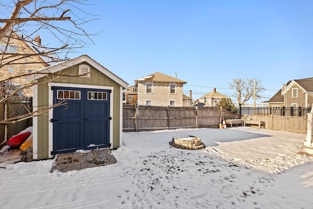 yard layered in snow featuring a storage shed and an outdoor fire pit