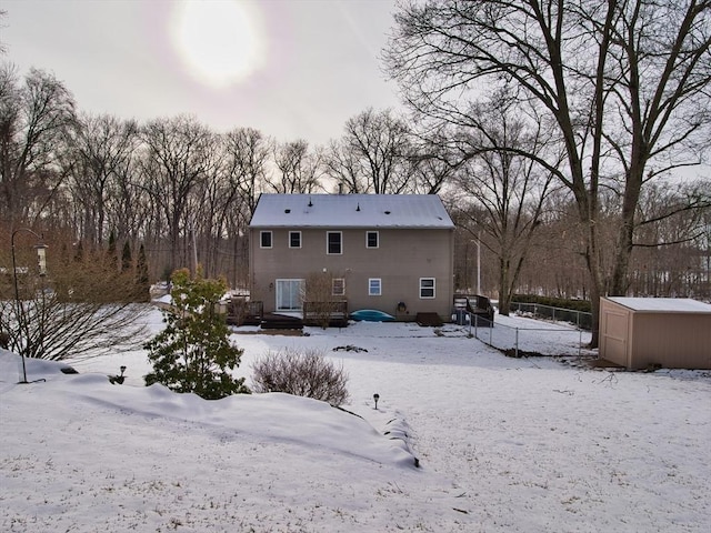 snow covered back of property with a storage shed