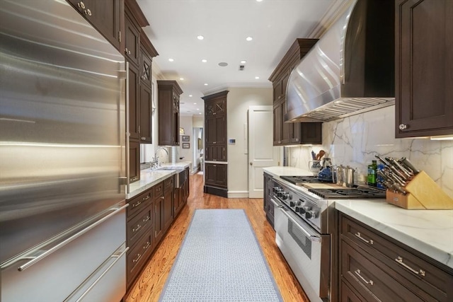36 Commonwealth Ave Unit 2, Boston, MA 02116 - kitchen with high quality appliances, wall chimney range hood, dark brown cabinetry, decorative backsplash, and crown molding