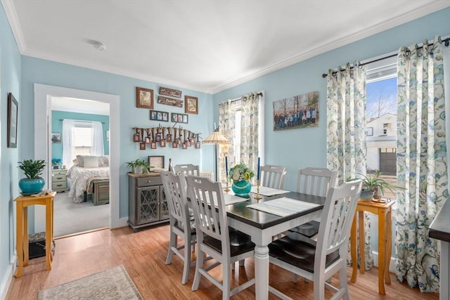 dining room featuring light wood-type flooring, crown molding, and baseboards