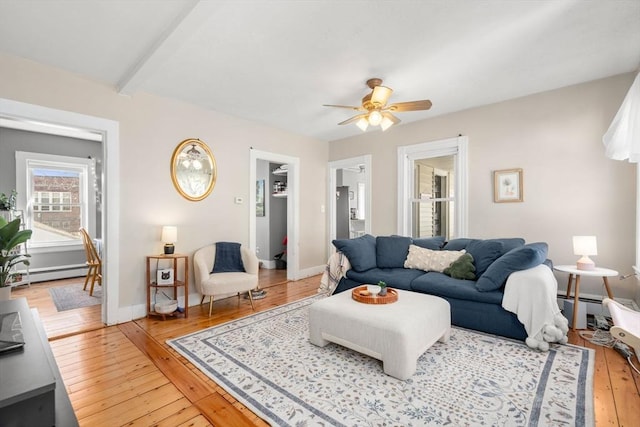 living area featuring a baseboard radiator, light wood-style floors, a ceiling fan, beam ceiling, and baseboards