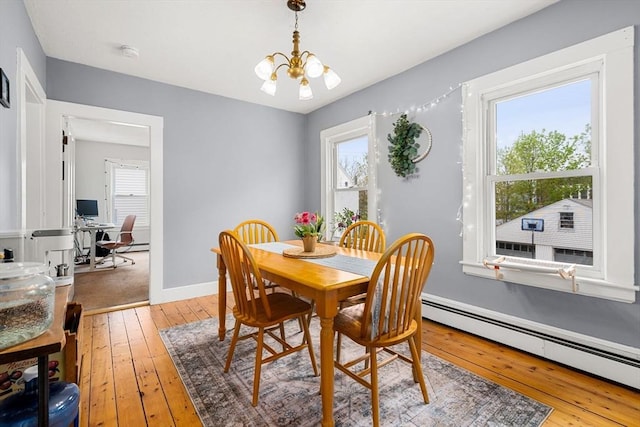 dining space featuring baseboard heating, a chandelier, light wood finished floors, and healthy amount of natural light
