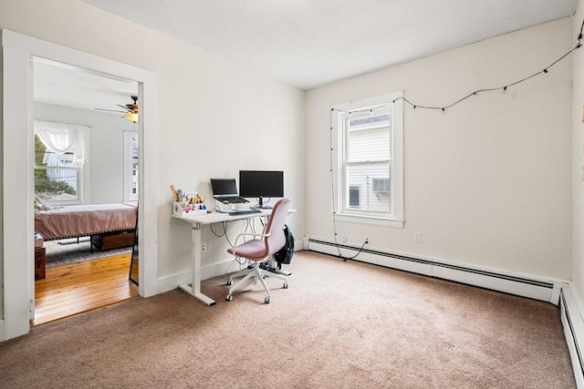 carpeted office space with plenty of natural light, a baseboard radiator, a ceiling fan, and baseboards