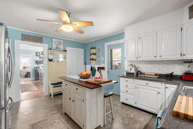kitchen with freestanding refrigerator, healthy amount of natural light, white cabinets, a ceiling fan, and crown molding