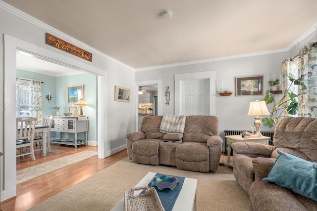 living area featuring wood finished floors, crown molding, a ceiling fan, and baseboards