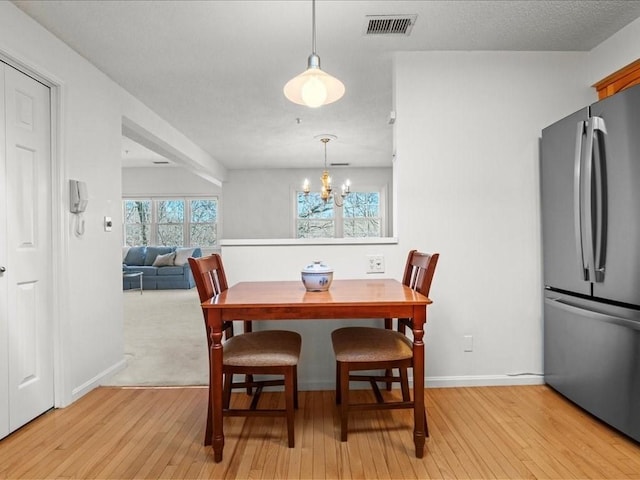 dining room with visible vents, baseboards, light wood-style flooring, and a chandelier