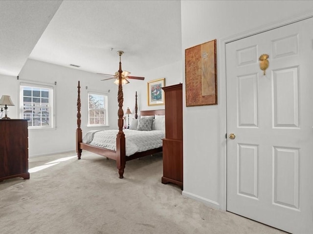 bedroom featuring ceiling fan, visible vents, baseboards, and light carpet