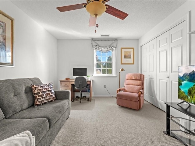 living area with a ceiling fan, baseboards, carpet, visible vents, and a textured ceiling