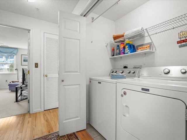 washroom featuring light wood-style floors, washing machine and dryer, laundry area, and a textured ceiling