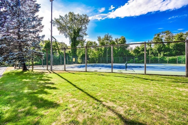 view of sport court featuring fence and a lawn