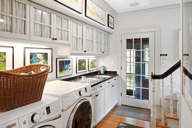 washroom with light wood-type flooring, cabinets, washer and clothes dryer, crown molding, and sink