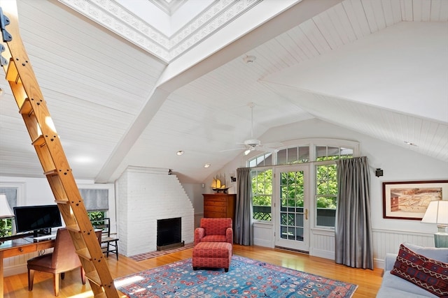 living room featuring lofted ceiling, light hardwood / wood-style flooring, ceiling fan, and a fireplace