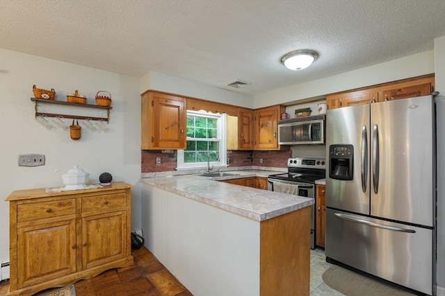 14 W Winkley St, Amesbury, MA 01913 - kitchen with stainless steel appliances, a peninsula, light countertops, a textured ceiling, and decorative backsplash