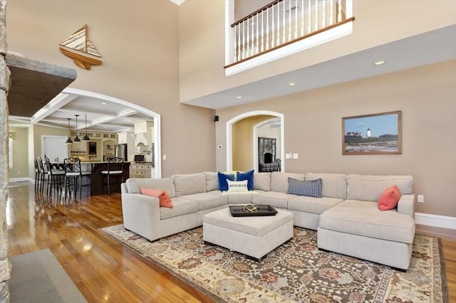 living room with hardwood / wood-style flooring, arched walkways, and coffered ceiling