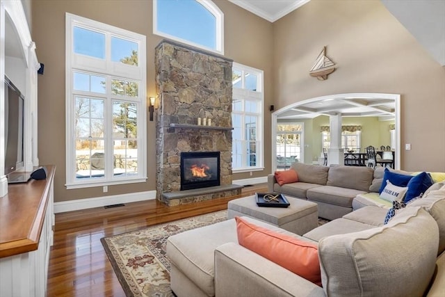 living room with a high ceiling, a fireplace, visible vents, and wood finished floors